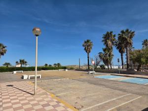 a park with benches and a street light and palm trees at Planta baja junto al mar con barbacoa in El Brosquil