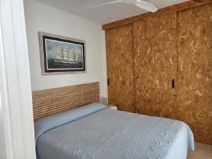 a bedroom with a bed with a wooden wall at Planta baja junto al mar con barbacoa in El Brosquil
