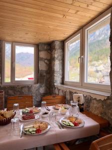 a table with plates of food on it with windows at Rosi peak Guesthouse in Valbonë