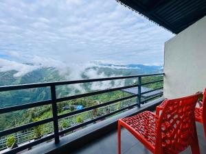 a balcony with red chairs and a view of the mountains at Living On The Edge A Luxury Stay in Mussoorie in Mussoorie +64 photos