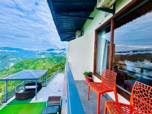 a balcony with two chairs and a view of mountains at Living On The Edge A Luxury Stay in Mussoorie in Mussoorie