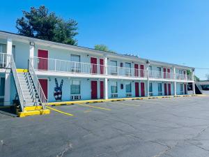 a large white building with red doors and a parking lot at Hometown INN in Berea