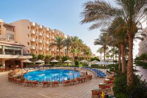 a resort with a pool and chairs and palm trees at Sea Star Beau Rivage Hotel in Hurghada