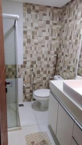 a bathroom with a toilet and a sink at Apart Condomínio Jubiabá in Ilhéus