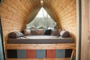 a bed in a wooden room with a window at Pod View-side river am clerve in Enscherange