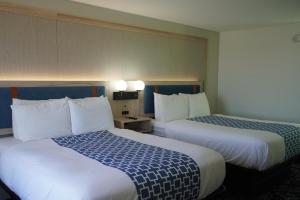 a hotel room with two beds and two lamps at Bay Inn & Suites Troy in Troy +2 photos