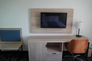 a room with a desk with a television on a wall at Bay Inn & Suites Troy in Troy