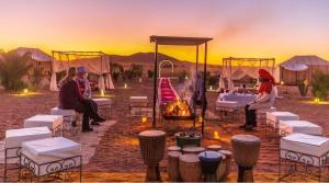a group of people sitting around a fire in a desert at Camp Merzouga Sand Explorer in Merzouga