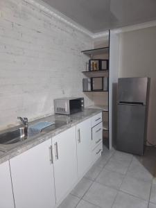 a kitchen with white cabinets and a stainless steel refrigerator at Vista Ree Guesthouse Pty Ltd in Taung