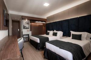 a hotel room with two beds and a television at Américas Benidorm Hotel in Rio de Janeiro