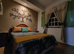 a bedroom with a bed with a tree on the wall at Pouso Elohim in Tiradentes