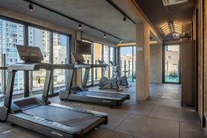 a gym with cardio equipment in a building with windows at Housi On Jardins in São Paulo