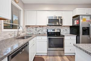 a kitchen with white cabinets and stainless steel appliances at 36 Bunker Court by Oak Island Accommodations in Caswell Beach