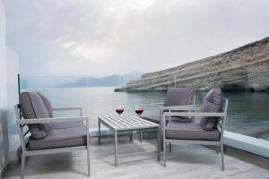 two chairs and a table with two glasses of wine at Thalassoresort UPSTAIRS in Matala