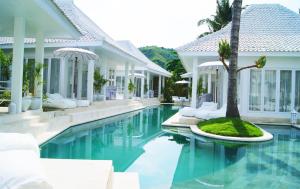 a pool at a villa with a palm tree in the middle at Harmony Villas in Kuta Lombok