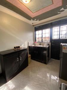 a kitchen with black cabinets and a sink and windows at Flat in Jinja City in Jinja