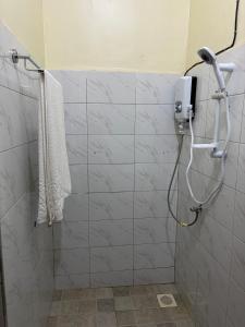 a shower in a bathroom with a white tiled wall at Sahel Gardens in Kisubi