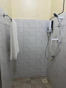 a shower in a bathroom with a white tiled wall at Sahel Gardens in Kisubi