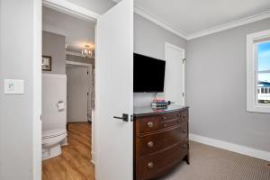 a bathroom with a toilet and a tv on a wall at 7th Heaven by Oak Island Accommodations in Oak Island