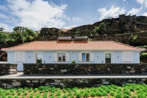 a white house with a stone wall at Casa Ti'Vina in Caniço