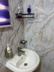 a bathroom with a white sink and a marble wall at Max Court in Ikeja