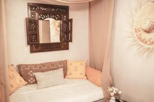 a couch with pillows and a mirror on a wall at La Cour Secrète - Riad & Balnéo privée in Carpentras