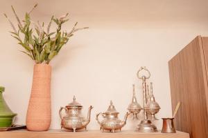 a shelf with a vase and a group of tea sets at La Cour Secrète - Riad & Balnéo privée in Carpentras +29 photos