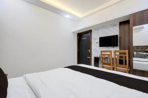 a bedroom with a white bed and a television at Hotel O White House in Rānchī