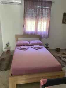 a bedroom with a bed with purple sheets and a window at Riverside in Virpazar