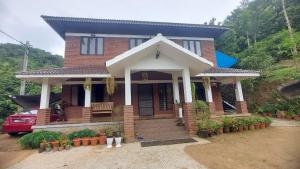 a house with a red car parked in front of it at Blue Hills View in Attappādi