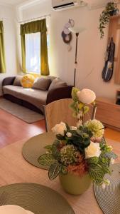 a living room with a table with a vase with flowers at Limonádé Apartman AC Agárd Élményfürdő mellett in Gárdony