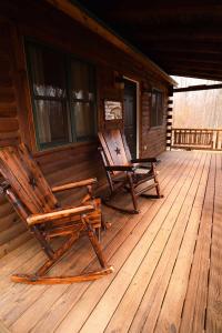 two rocking chairs sitting on the porch of a cabin at Secluded Cozy Log Cabin Villa in Creola