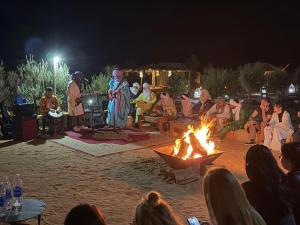 a group of people standing around a fire at night at Merzouga Traditional Camp in Merzouga