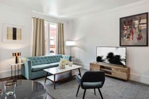 a living room with a blue couch and a tv at Contemporary Condo Downtown Savannah in Savannah