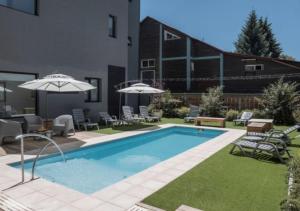 a pool with chairs and umbrellas next to a building at Gluck Patagonia Aparts in Villa La Angostura