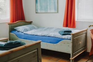 a bedroom with a bed with blue sheets and red curtains at Friesenpark 8 in Wurster Nordseeküste