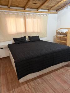 a bedroom with a large bed with black sheets at Casa verde in Vichayito