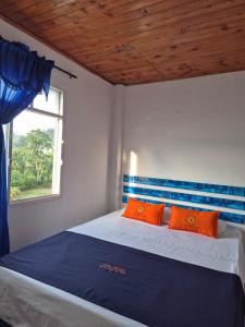 a bedroom with a bed with orange pillows and a window at Hotel Girasol in Santa Rosa de Cabal