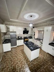 a large kitchen with white cabinets and black counter tops at Goshen in Iju Junction