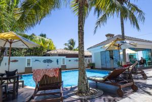 a pool with chairs and palm trees next to a house at Golfinhos Apart Hotel in Florianópolis