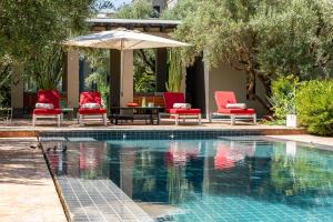 a pool with two chairs and an umbrella and a table and chairs at Villa ouidane in Marrakesh