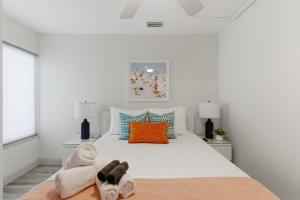 a bedroom with a white bed with towels on it at Be A Nomad - 2BR Jacksonville Beach Apartment - 1 Min to Beach - Sleeps 4 in Jacksonville Beach +14 photos