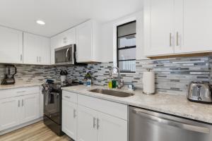 a kitchen with white cabinets and a sink at Be A Nomad - 2BR Jacksonville Beach Apartment - 1 Min to Beach - Sleeps 4 in Jacksonville Beach