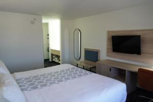 a bedroom with a bed and a desk with a television at Bay Inn & Suites Troy in Troy