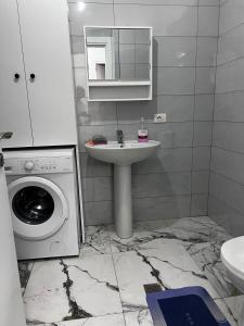 a bathroom with a sink and a washing machine at Holiday apartaments Gaca in Lezhë