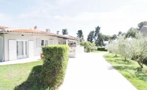 a white house with a hedge in front of it at House PUNTA II in Umag