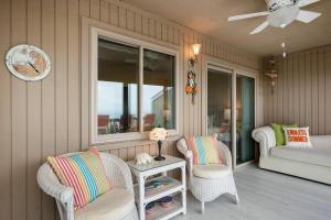 a porch with two chairs and a table and a couch at A Searious Sunset View by Oak Island Accommodations in Caswell Beach