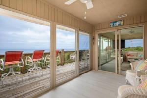 a screened in porch with rocking chairs and windows at A Searious Sunset View by Oak Island Accommodations in Caswell Beach