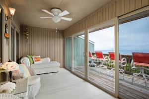 a living room with a ceiling fan and a balcony at A Searious Sunset View by Oak Island Accommodations in Caswell Beach