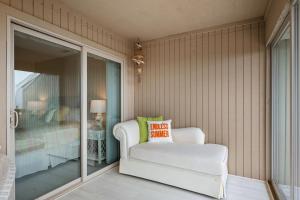 a white chair in a room with a bedroom at A Searious Sunset View by Oak Island Accommodations in Caswell Beach